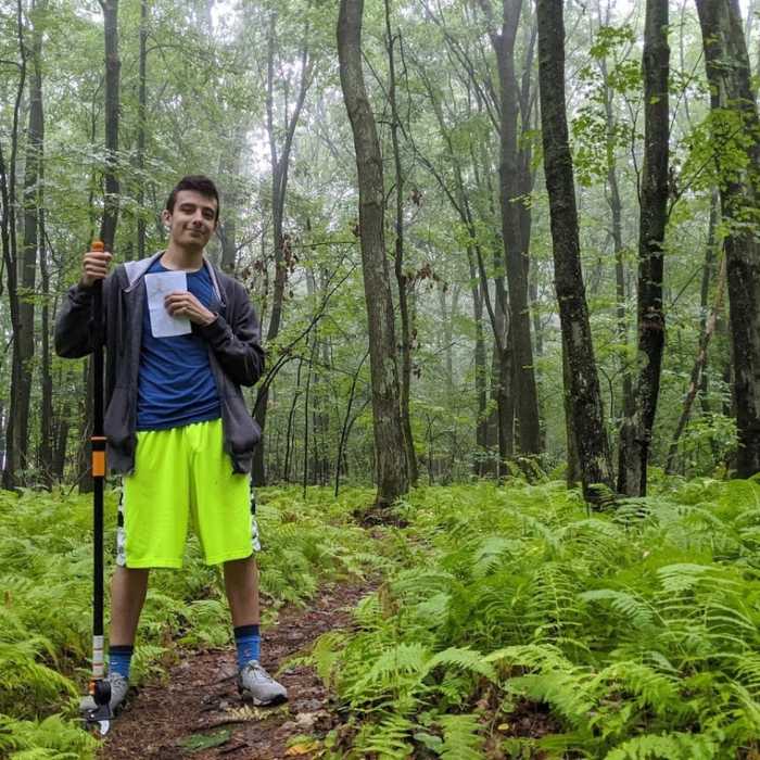 Volunteer taking trail measurements and mitigating poison ivy Near Jericho Hill Red, White & Blue route