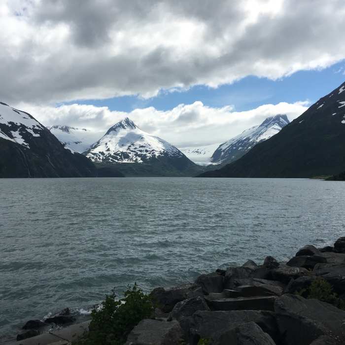 Snow-capped mountains see the sun peek through the clouds in the middle of summer on the Kenai Peninsula. Near Portage Glacier (Winter)