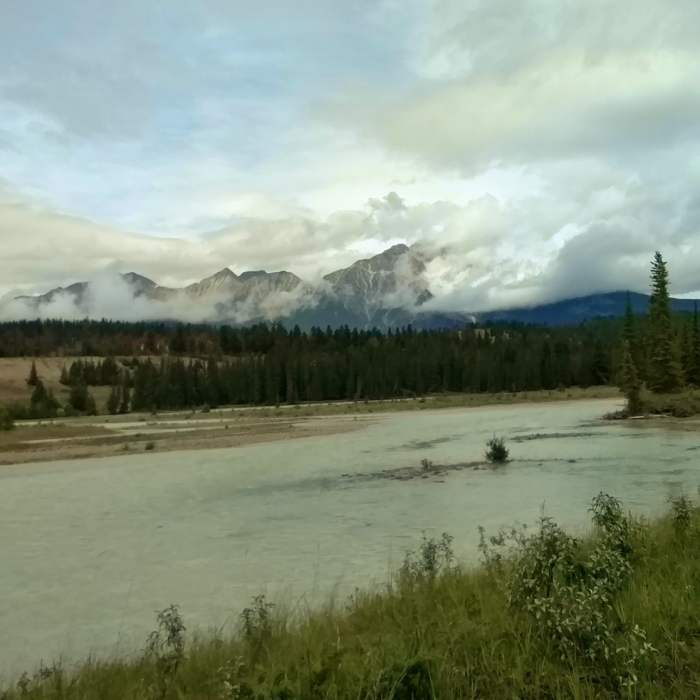 A side channel of the Athabasca River with Pyramid Mountain in the distance (center) partly hidden in the clouds, looking northwest from the Athabasca River Trail. Near Athabasca River Trail