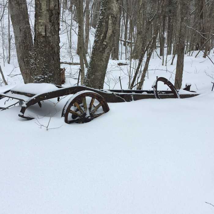 Old farm equipment or old car with wooden wheel spokes. Near Broad Brook Trail