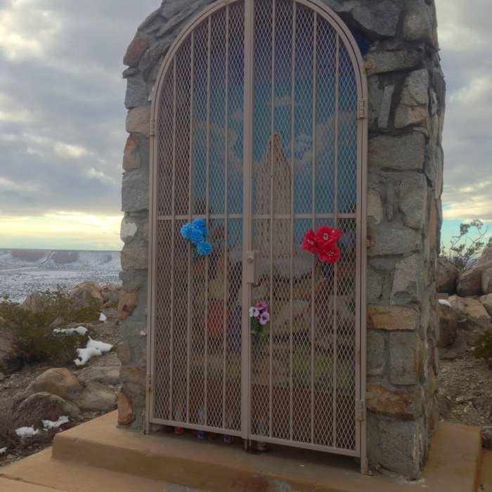 One of the trail's shrines, this one to the Virgin of Fatima. It is kept locked on non-event days. In the distance, the border fence can be seen crawling up the mesa, marking the international boundary. Near Mount Cristo Rey