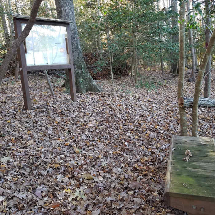 Resting bench and trail map with view of lake to the right of photo. Near Poe's Ridge Trail