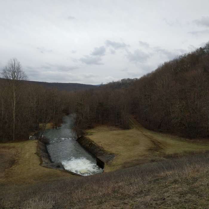 The downstream side of the dam harbors dense hardwood forests and a raging outflow. Near Lake Shore Trail